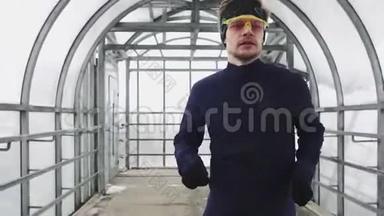 跑步男子在运动服锻炼前三项全能，冲刺玻璃隧道。